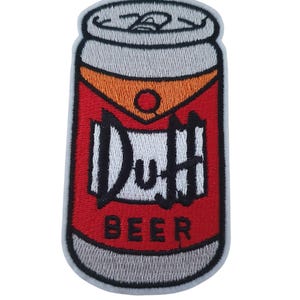 May include: Embroidered patch featuring a cartoon beer can design. The can is red with orange and white accents, and the text "Duff BEER" in black. The patch has a gray border and is likely for clothing or accessories.