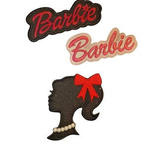 May include: Three embroidered patches featuring the word "Barbie" in a cursive font and a silhouette of a woman's profile. The word "Barbie" is in red on a black and a light pink background. The silhouette is black with a red bow and pearl necklace.