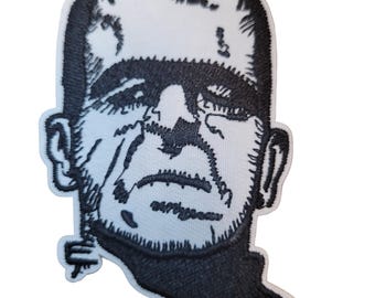 Può includere: Toppa ricamata in bianco e nero con un ritratto stilizzato del mostro di Frankenstein. La toppa ha uno sfondo bianco con un contorno e un'ombreggiatura neri dettagliati, che raffigurano le caratteristiche iconiche del mostro.
