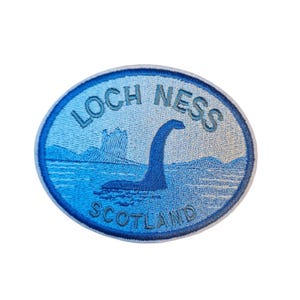 Op de afbeelding: Ovale patch met een blauwe gradiënt achtergrond. De patch toont de tekst "LOCH NESS" en "SCOTLAND", samen met een illustratie van het Loch Ness Monster en een kasteel.