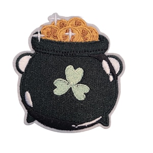May include: Embroidered patch featuring a black pot filled with gold coins, a green shamrock, and a white outline. This patch is perfect for St. Patrick's Day or adding a touch of luck to clothing or accessories.