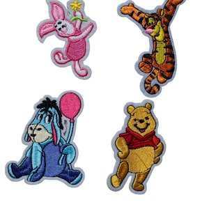 Könnte beinhalten: Vier gestickte Aufnäher mit Figuren aus Winnie Puuh. Enthält Ferkel mit einer Blume, Tiger springend, I-Aah mit einem Ballon und Winnie Puuh in einem roten Hemd.