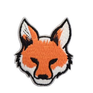 Op de afbeelding: Geborduurde patch met een vossenkop. De vos heeft oranje vacht met witte en zwarte accenten. De patch is zwart omlijnd en waarschijnlijk bedoeld om op stof te strijken of te naaien. Een schattig en grillig ontwerp.