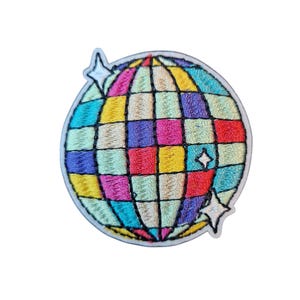 Può includere: Toppa ricamata con un design a palla da discoteca colorata. La toppa presenta un motivo a griglia con quadrati di vari colori, tra cui rosso, giallo, blu e viola. Due stelle bianche sono ai lati.