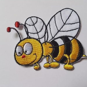 May include: Embroidered bee patch featuring a smiling cartoon bee with yellow and black stripes, white wings, and red antennae. Ideal for adding to clothing or accessories.