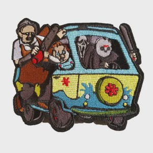 Peut inclure: Écusson brodé représentant une camionnette bleue et jaune avec des personnages de films d'horreur. Les personnages incluent un homme avec une tronçonneuse, Chucky, Ghostface et Jason Voorhees. La camionnette a une fleur sur le pneu et une étoile rouge.