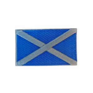 Könnte beinhalten: Ein rechteckiger Aufnäher mit der schottischen Flagge. Das Design zeigt einen blauen Hintergrund mit einem weißen Andreaskreuz. Die Ränder des Aufnähers sind mit einem grauen Rand versehen.