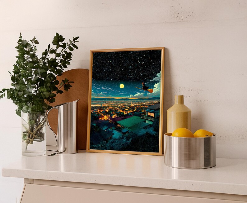 May include: A framed art print depicts a night scene with a witch flying on a broom over a city. The artwork features a starry sky, a full moon, and a vibrant cityscape with illuminated buildings. The frame is a light brown color.