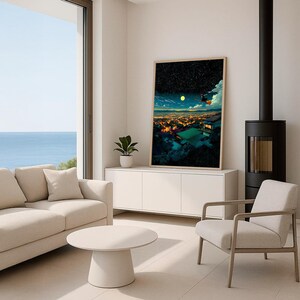 May include: A modern living room with a large framed art print depicting a nighttime cityscape with a full moon. The room features a beige sofa, a round coffee table, and a white cabinet. A black fireplace and a large window with a view of the ocean are also visible.
