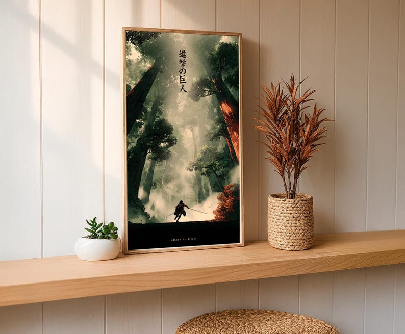 May include: A framed art print featuring a dramatic forest scene with a silhouetted figure. The artwork has a vertical orientation and includes Japanese text at the top and the words "attack on titan" at the bottom. The print is displayed on a wooden shelf.