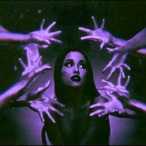 May include: A portrait of a person with dark hair and dark lipstick, illuminated in a vibrant purple hue. Multiple hands reach toward the center from the edges of the frame, creating a layered effect against a dark, moody background.