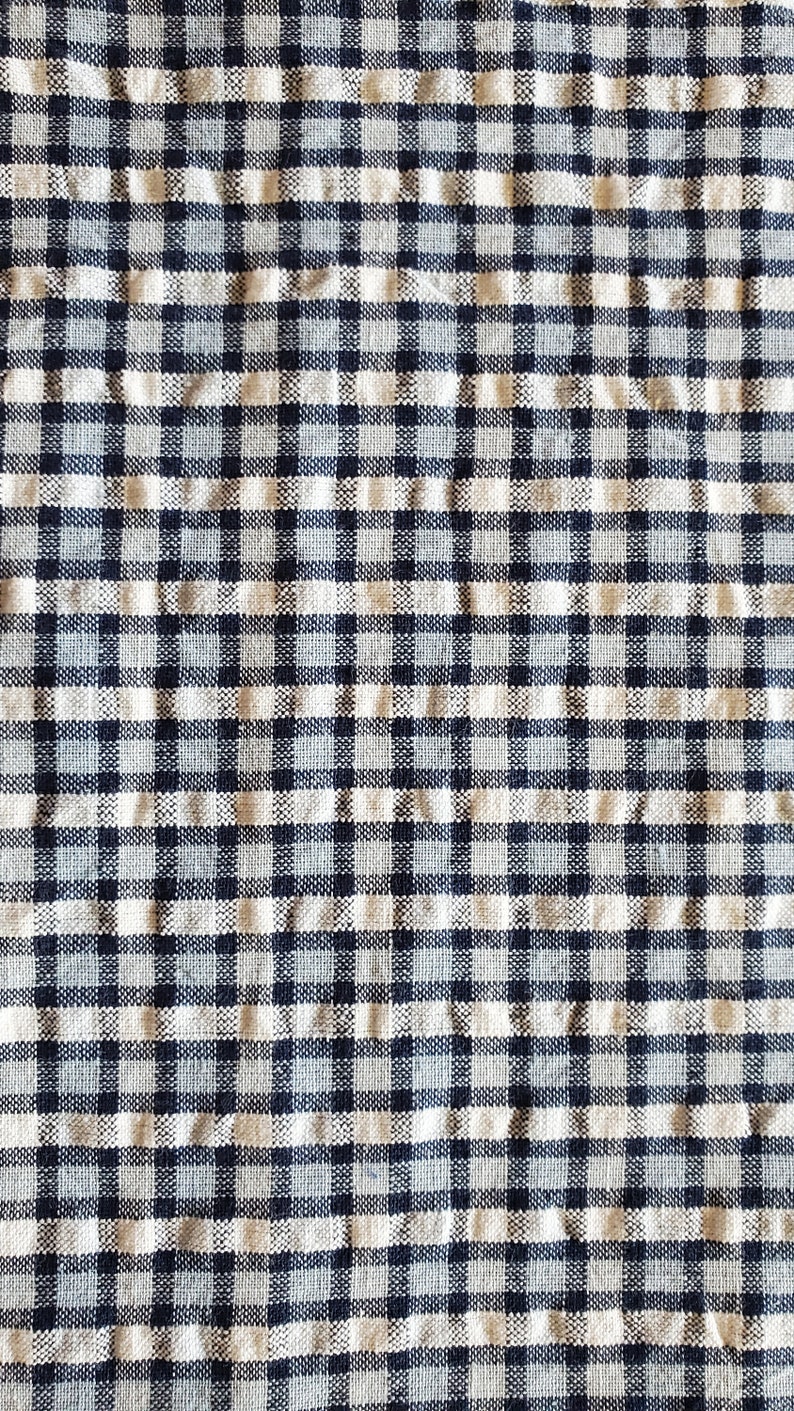 May include: A close-up of a white and black checked fabric with a woven texture.