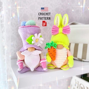 May include: Two crochet gnome figures. One is wearing a purple hat and holding a flower, the other is wearing a bunny hat and holding a carrot. The text "CROCHET PATTERN" is above a PDF icon.