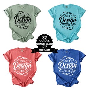 Puede incluir: Cuatro camisetas en varios colores: verde salvia, turquesa, coral y azul. Cada camiseta presenta el texto "Your Design Here" en una escritura decorativa. Un gráfico en blanco y negro indica 32 opciones de color.