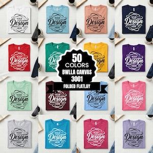 以下が含まれることがあります： さまざまな色のTシャツのフラットレイ。各Tシャツには、様式化されたフォントで「Your Design Here」というテキストが表示されています。画像には、「50 COLORS BWLLA CANVAS 3001 FOLDED FLATLAY」と書かれた中央のグラフィックが含まれています。