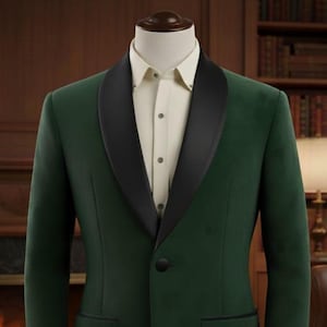 Może przedstawiać: Ciemnozielona marynarka z czarnymi klapami i kremową koszulą. Marynarka ma jeden czarny guzik i dwie kieszenie. Garnitur jest prezentowany na manekinie.