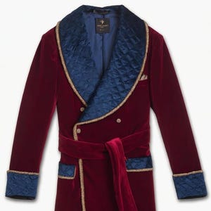 May include: A burgundy velvet robe with a quilted navy blue collar and cuffs, trimmed with gold piping. The robe features a matching belt and pockets, offering a luxurious and elegant design. The robe has a double-breasted closure.