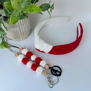 May include: A red and white beaded lanyard with a baseball charm and a silver key chain. A red and white headband is also included.