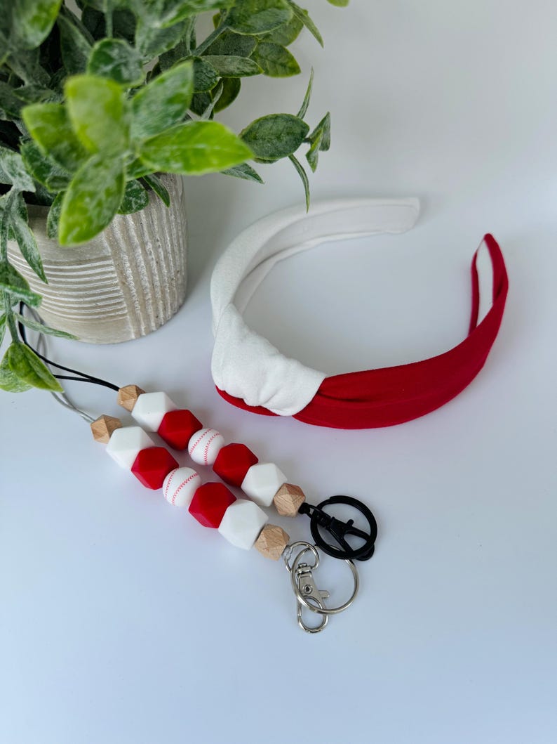 May include: A red and white beaded lanyard with a baseball charm and a silver key chain. A red and white headband is also included.