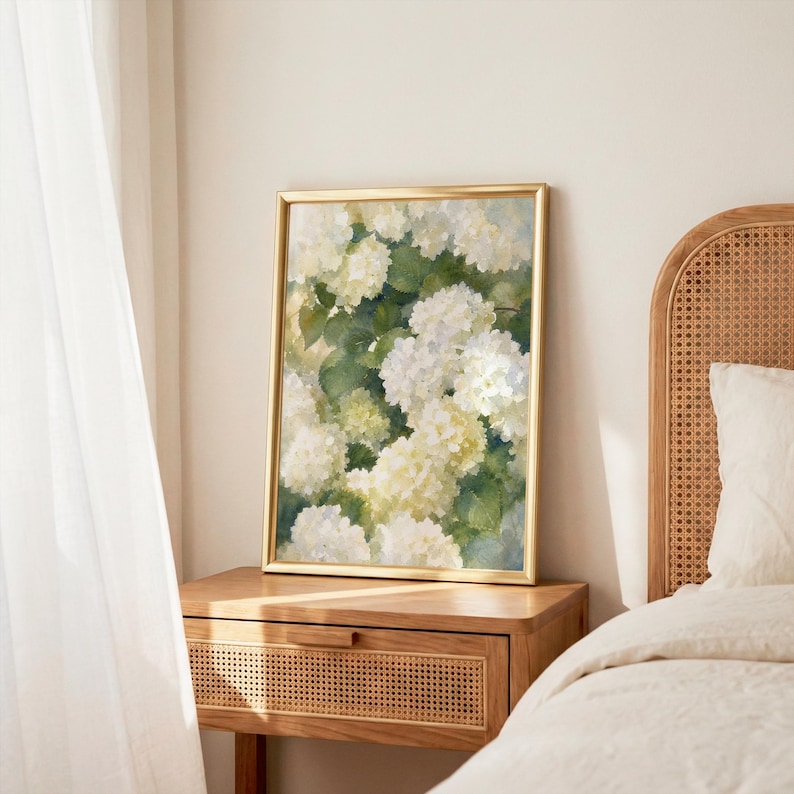 May include: A framed vertical wall art print featuring a detailed painting of white hydrangea flower clusters nestled among deep green foliage. The artwork is encased in a thin, metallic gold frame, showcasing a botanical floral composition.
