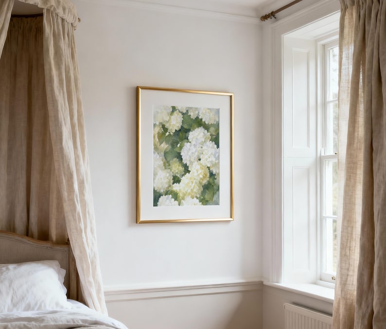 May include: A rectangular wall art print featuring a watercolor painting of white and pale yellow hydrangea flowers with green foliage, encased in a thin metallic gold frame with a wide white mat border, displayed on a plain white wall.
