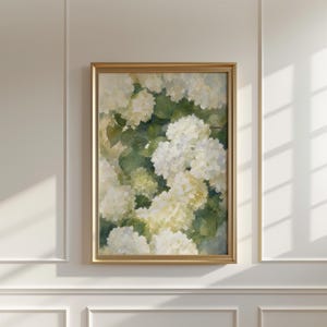May include: A vertical rectangular wall art piece featuring a watercolor painting of white hydrangea flowers with soft yellow centers and deep green leaves, enclosed within a thin, metallic gold frame that highlights the botanical composition.