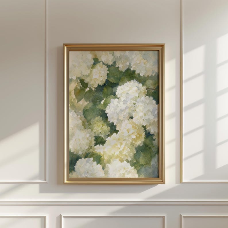May include: A vertical rectangular wall art piece featuring a watercolor painting of white hydrangea flowers with soft yellow centers and deep green leaves, enclosed within a thin, metallic gold frame that highlights the botanical composition.