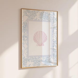 Könnte beinhalten: Gerahmter Kunstdruck mit einer rosa Muscheldarstellung. Der goldfarbene Rahmen umgibt einen hellblauen Blumenrand. Der Hintergrund ist ein weiches Beige, das eine elegante, maritime Ästhetik erzeugt. Größe ca. 30 x 40 cm.