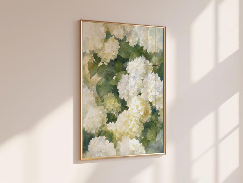 May include: A vertical rectangular wall art print in a thin gold frame featuring a watercolor painting of white and cream hydrangea flowers with green leaves. The artwork displays soft brushstrokes and a botanical theme with light tones.