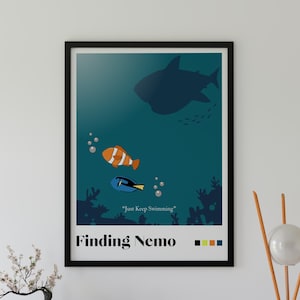 May include: A framed wall art print featuring a dark teal underwater scene with a silhouette of a shark, an orange and white clownfish, and a blue tang fish. The text reads "Just Keep Swimming" and "Finding Nemo" with four small color squares.