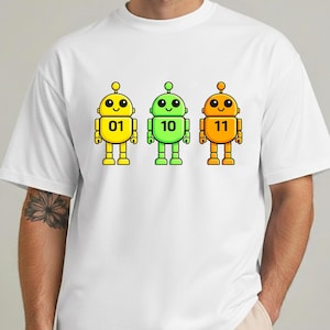 May include: White t-shirt featuring three cartoon robots in yellow, green, and orange. Each robot has a number: 01, 10, and 11. The robots have smiling faces and are outlined in black. The design is centered on the shirt.