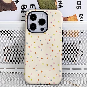 May include: A cream-colored phone case adorned with a pattern of colorful stars. The case has a black camera ring and buttons. The stars are in shades of red, orange, yellow, green, blue, and purple.