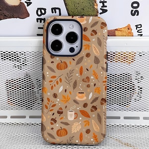 Può includere: Una custodia per telefono beige con un motivo a tema autunnale. Il design include zucche, foglie, tazze di caffè, ghiande e cuori nei toni del marrone, arancione e bianco. La custodia ha un bordo nero attorno alla fotocamera.
