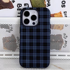 Puede incluir: Una funda de teléfono a cuadros azul marino y negro. La funda tiene un diseño de patrón de cuadrícula. La funda del teléfono está hecha de un material duro y protector. La funda del teléfono está diseñada para adaptarse a un teléfono inteligente.