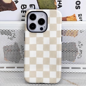 Pode incluir: Uma capa de telefone com um padrão xadrez bege e branco. A capa tem um anel de câmera preto e um acabamento brilhante. O design é um padrão clássico e simples.