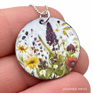 May include: A white ceramic mug with a black handle and the text "But First, Coffee" in a bold, black font. The mug is set against a blurred background, suggesting a cozy setting. The mug appears to be approximately 4 inches tall.