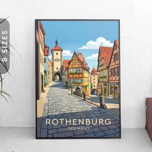 以下が含まれることがあります： ドイツ、ローテンブルクのカラフルなイラストが描かれた、額入りのアートプリント。歴史的建造物、塔、雲のある青い空が並ぶ石畳の通りが描かれています。「ROTHENBURG GERMANY」の文字が下部にあります。