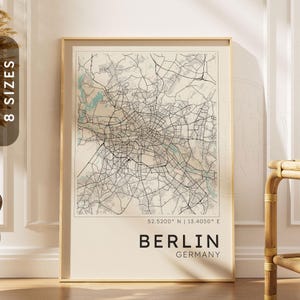 Op de afbeelding: Een ingelijste wandkunstprint met een gedetailleerde zwart-wit stadsplattegrond van Berlijn, Duitsland. De kaart bevat de geografische coördinaten 52.5200 N | 13.4050 E, met de stadsnaam BERLIN en GERMANY in vetgedrukte zwarte letters.