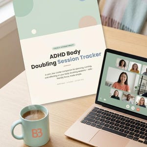 May include: A document titled ADHD Body Doubling Session Tracker with a BrainBeam logo, a laptop displaying a video call with multiple participants, a light blue mug with a B3 logo, and a light blue pen on a wooden surface.