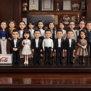 Pode incluir: Um grupo de figuras em miniatura de pessoas vestidas com roupas de negócios está em uma base de madeira escura. Uma placa da Coca-Cola está na frente. O fundo inclui uma mesa, uma planta e uma prateleira com prêmios.