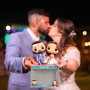May include: A Funko Pop-style figurine set of a bride and groom, held in front of a kissing couple. The groom figurine wears a blue suit, and the bride wears a white dress. The box below has the word "NAME" printed on it.