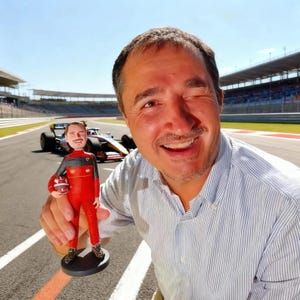 Pode incluir: Miniatura de um piloto de Fórmula 1 com um fato de corrida vermelho, segurando um capacete. A figura está sobre uma base preta. Um carro de corrida de Fórmula 1 está no fundo em um circuito.