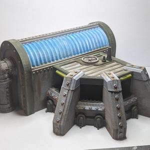 May include: A detailed model of a futuristic structure, featuring a cylindrical component with blue, ribbed detailing and a rectangular base. The model is primarily grey with metallic accents, suggesting a sci-fi or industrial theme. The design includes pipes and rivets.