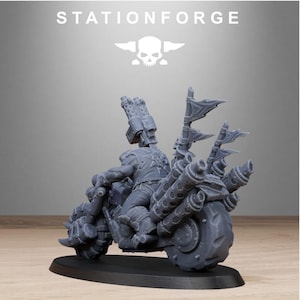 Puede incluir: Una motocicleta en miniatura gris con un piloto, con grandes tubos de escape, banderas y un arma montada. La motocicleta est&aacute; sobre una base negra, con el texto "STATIONFORGE" y un logotipo de calavera encima.