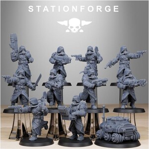 Op de afbeelding: Een verzameling grijze miniatuurbeeldjes van soldaten en een kleine tank. De beeldjes staan in verschillende actiehoudingen en houden wapens vast. De tekst "STATIONFORGE" en een schedellogo staan bovenaan.