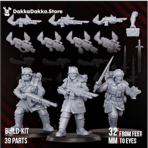 May include: A grey resin miniature build-kit featuring three soldier figures in military uniforms with helmets and goggles, plus various weapon and equipment parts. The text DakkaDakka.Store, 39 parts, and 32 mm from feet to eyes are visible.