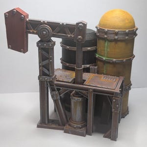 May include: A miniature industrial model with a rusty, weathered appearance. The model features a red and brown pump jack, cylindrical tanks, and a yellow dome-shaped structure. The overall design suggests a vintage or steampunk aesthetic.