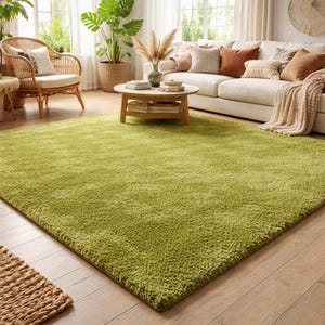 May include: A large, rectangular, solid lime green area rug with a thick, plush, shaggy texture. The rug is positioned on a light-toned wooden floor, covering a significant portion of the foreground and extending toward a living room furniture set.