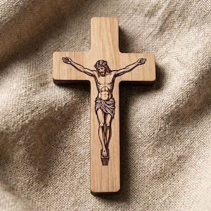 May include: A light brown wooden crucifix featuring a dark brown laser-engraved depiction of the figure of Jesus Christ on the cross. The wooden cross has a smooth, flat surface with visible natural wood grain patterns throughout the structure.
