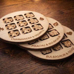 May include: Three circular wooden game boards featuring laser-engraved grid patterns and character icons. The boards are labeled with text including Charmander & Squirtle, Pikachu & Bulbasaur, and Bulbasaur & Eevee, with small fire, water, leaf, and heart symbols.